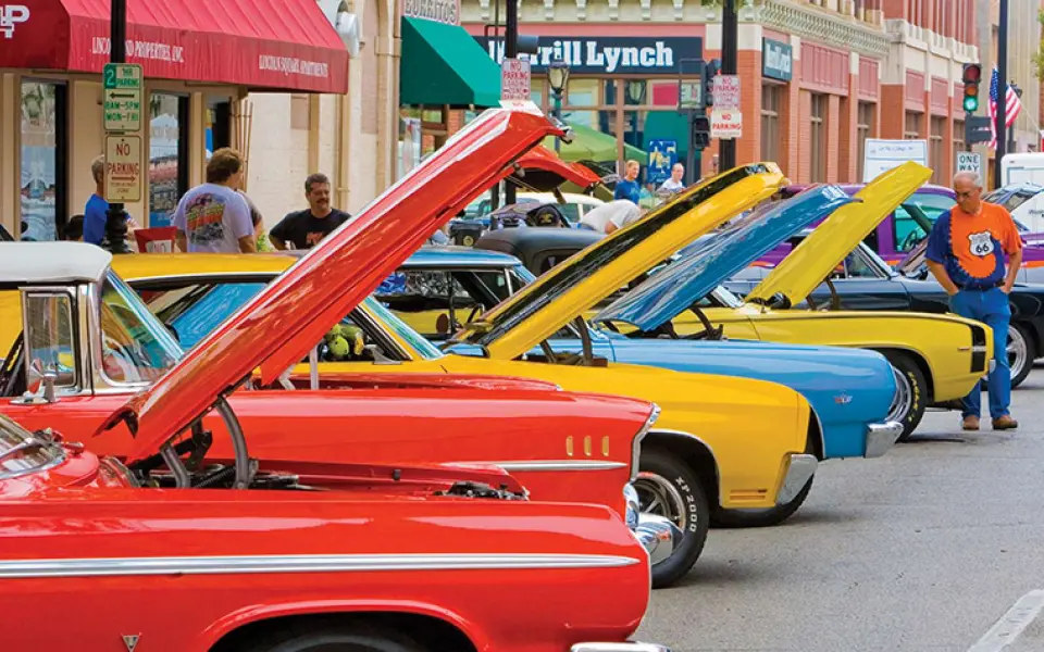 Coches clásicos de colores vivos, con el capó levantado, se alinean en una calle del centro de la ciudad durante una exposición de la Route 66 « automóvil ».