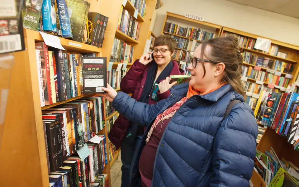 Mujeres en una librería mirando una estantería de libros