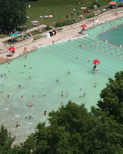 Vista aérea de una playa de cantera rellenada, con gente en el agua y en la orilla.