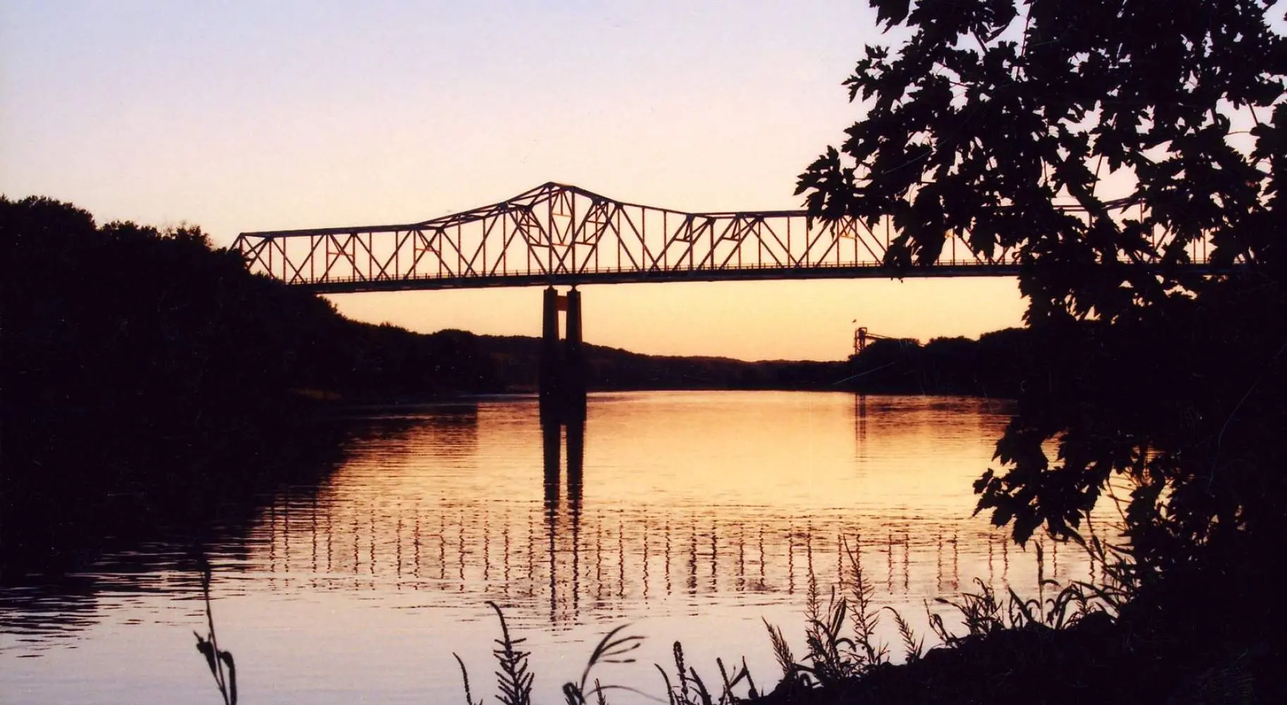 Un puente sobre un río al atardecer, visto desde la orilla