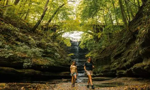 Dos niñas caminan frente a una cascada en el Parque Estatal Matthiessen