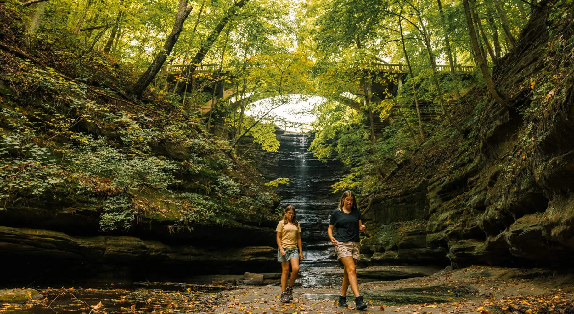 Dos niñas caminan frente a una cascada en el Parque Estatal Matthiessen