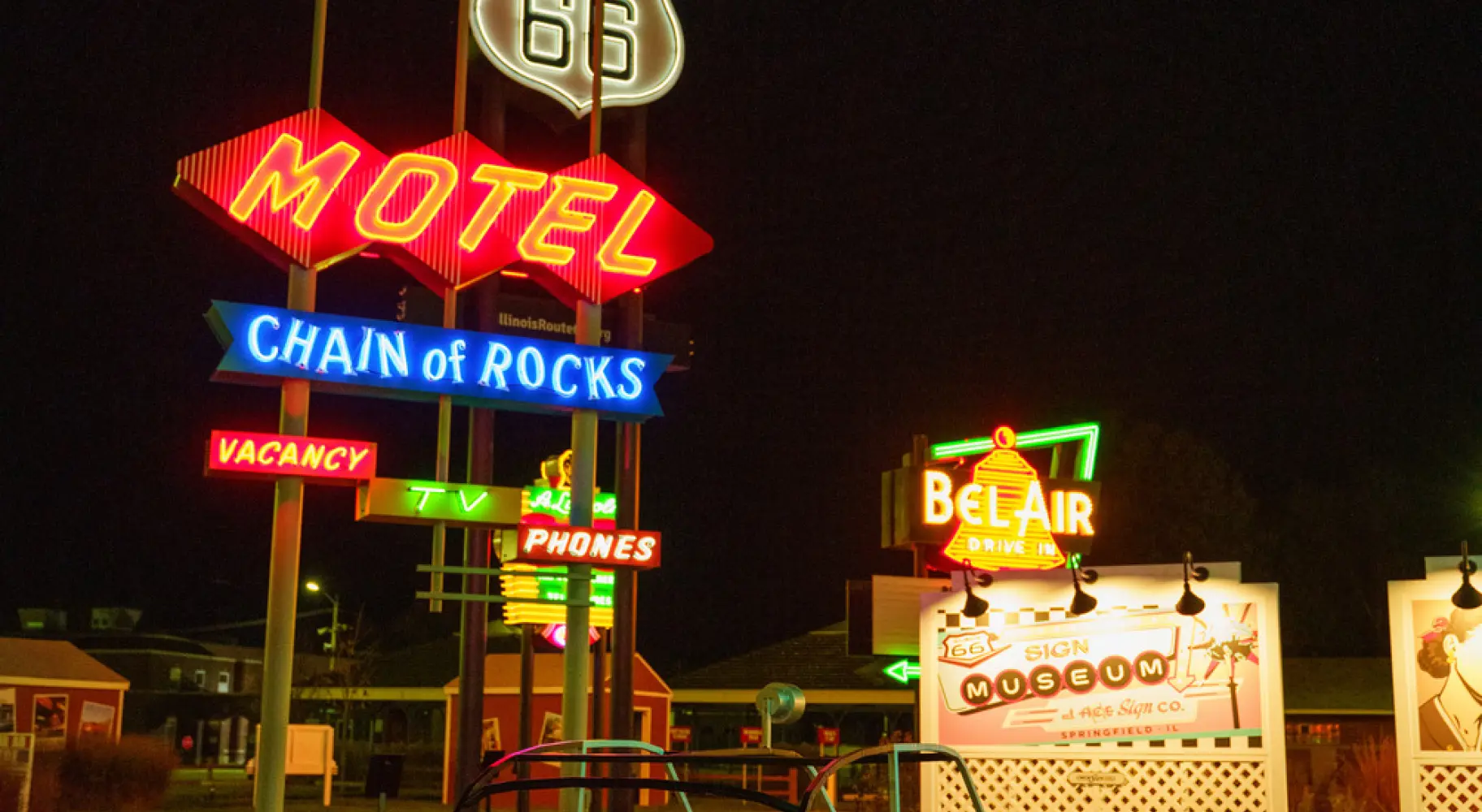 Letreros vintage de neón de moteles de la Ruta 66 y un clásico « automóvil » de pedales iluminados por la noche.