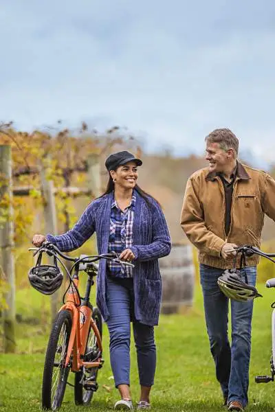 Una pareja paseando con sus bicicletas entre las viñas