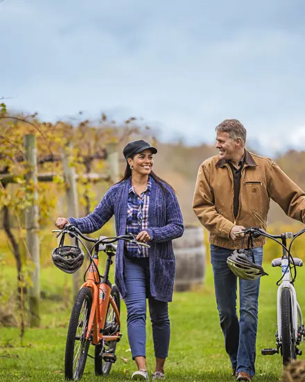 Una pareja paseando con sus bicicletas entre las viñas