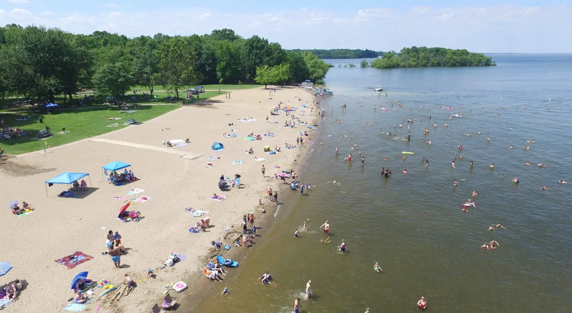 Una vista aérea de una playa con gente disfrutando del sol, la arena y el agua