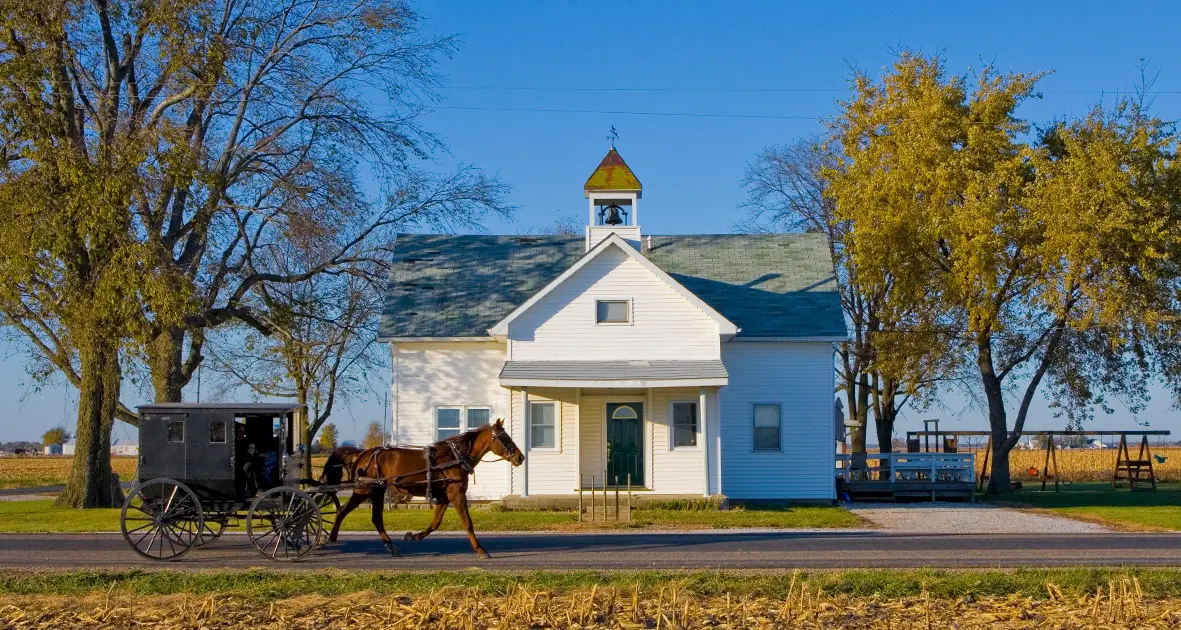 Carruaje de caballos pasando por delante de un edificio Amish 