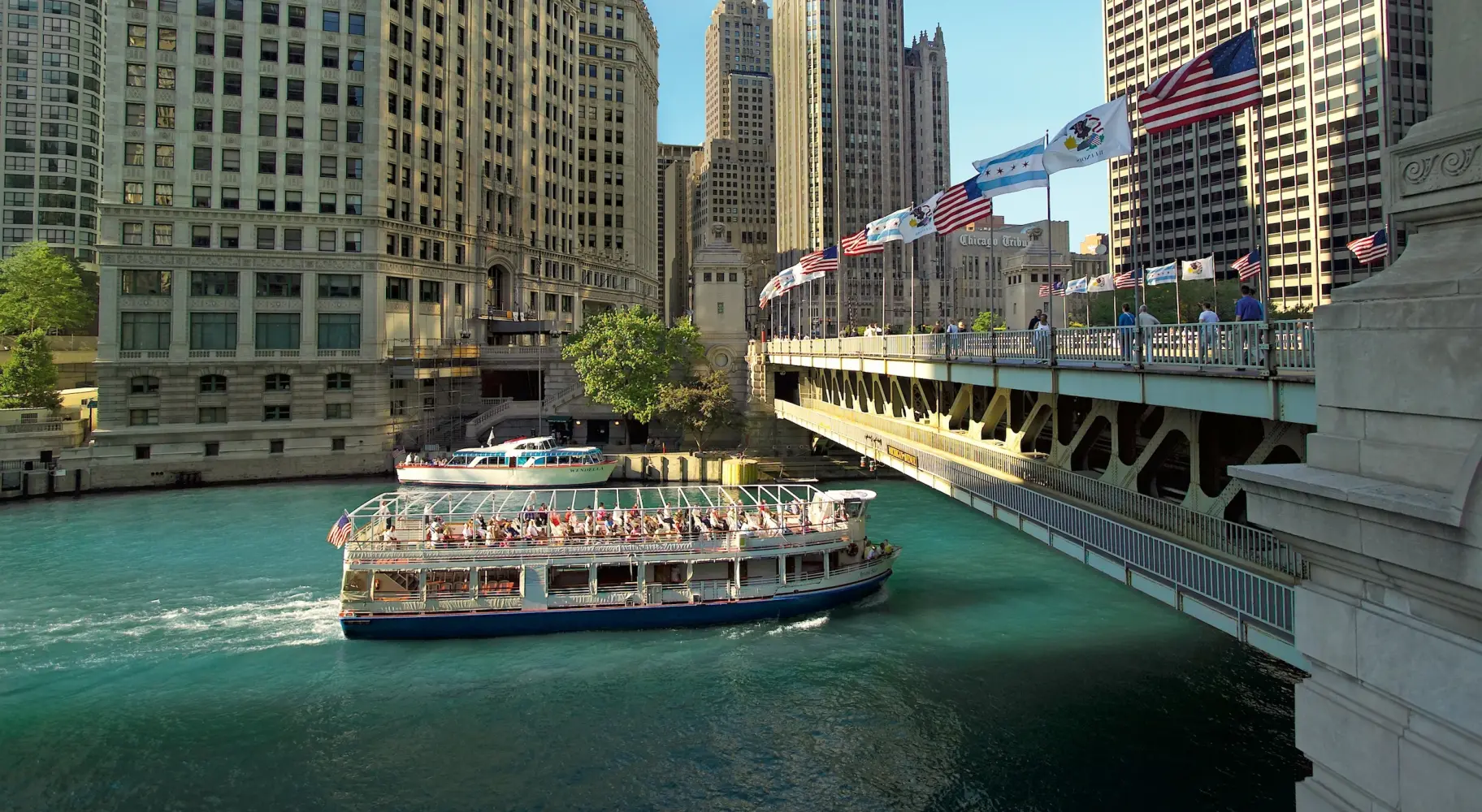 Un barco turístico de arquitectura pasa bajo un puente en Chicago.