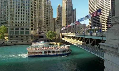 Un barco turístico de arquitectura pasa bajo un puente en Chicago.