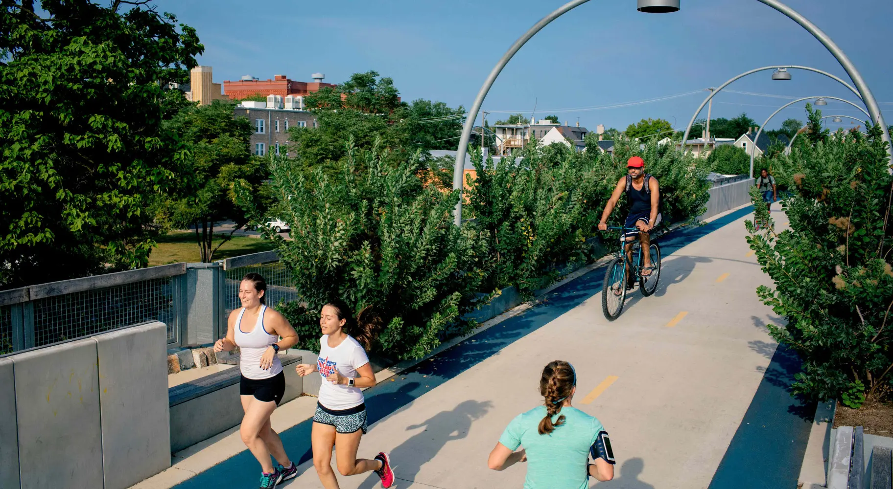 Gente corriendo y andando en bici por el puente para bicicletas 
