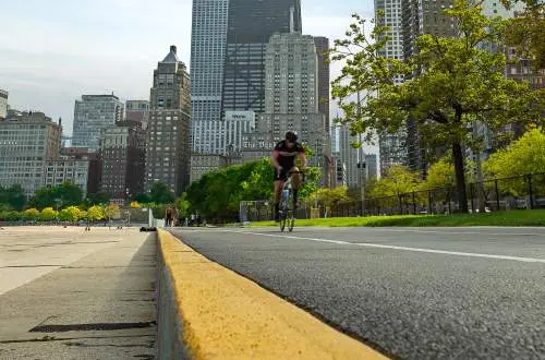 Una ciudad detrás de un hombre en bicicleta por una carretera
