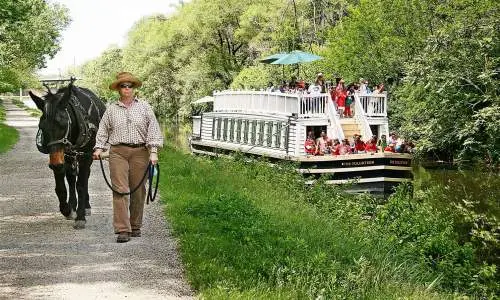 Una mujer pasea a caballo junto al canal al paso del barco del canal I&M