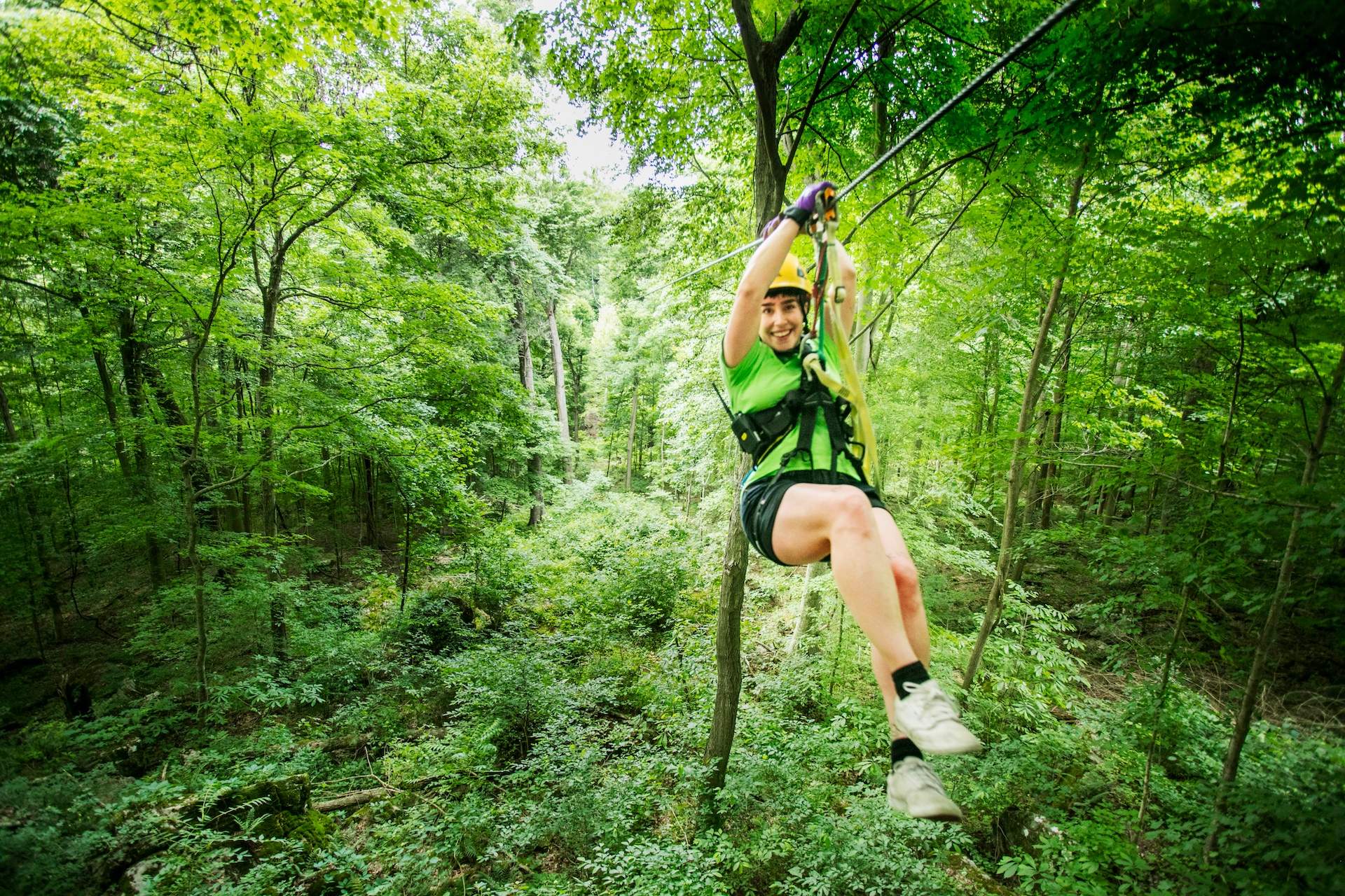 Una mujer se desliza por una línea desde un zorro volador entre los árboles