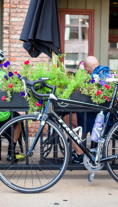 Ciclistas tomando un café con sus bicicletas aparcadas fuera de la cafetería.