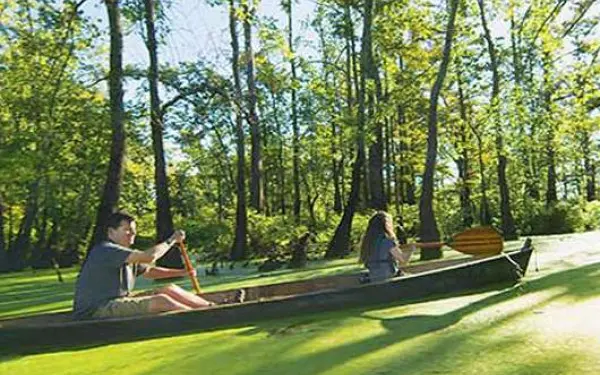 Imagen lateral de un padre y su hija navegando en canoa por un río pantanoso.