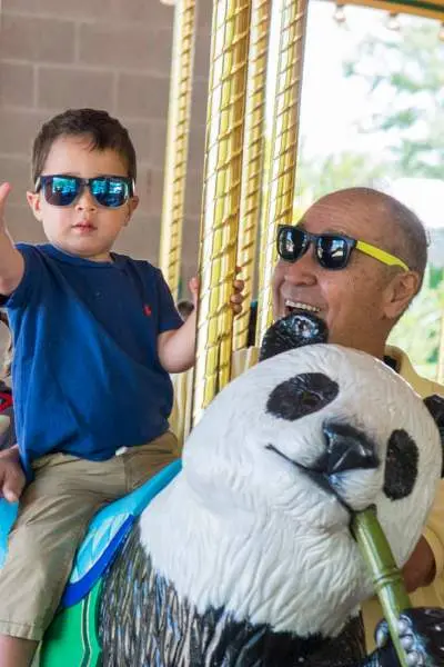 Un niño pequeño y sus abuelos en el carrusel del zoo de Brookfield.