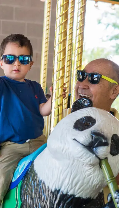 Un niño pequeño y sus abuelos en el carrusel del zoo de Brookfield.