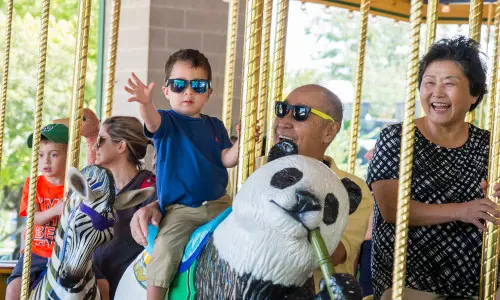 Un niño pequeño y sus abuelos en el carrusel del zoo de Brookfield.