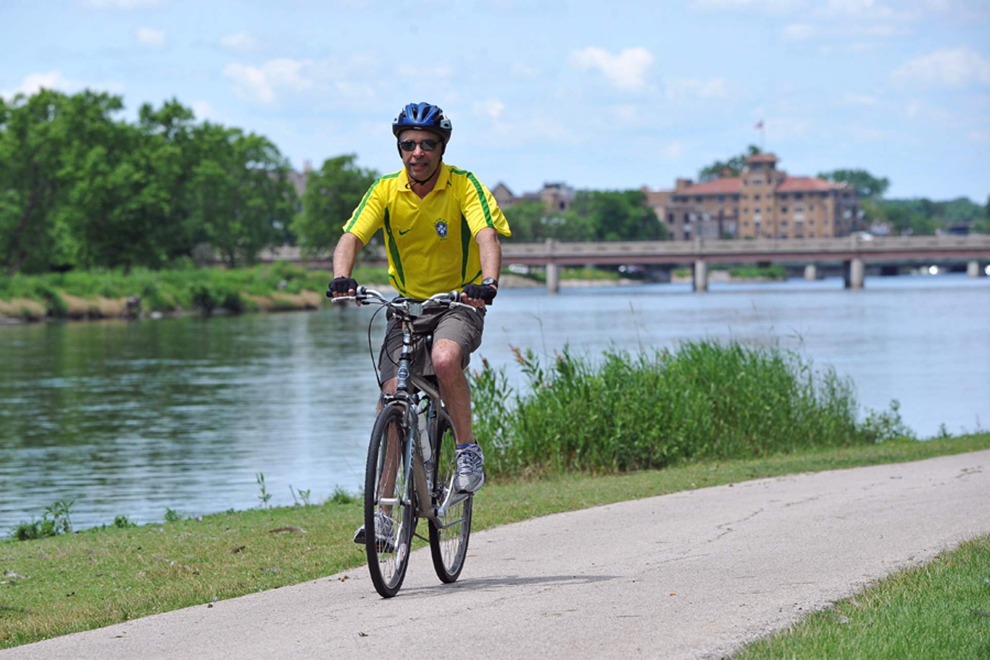 Un hombre con una camiseta amarilla brillante pedalea por un sendero junto al río Fox