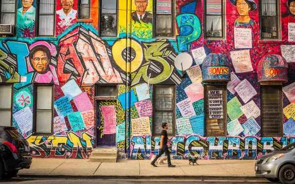 Una persona con un perro paseando delante de un mural de la herencia mexicana