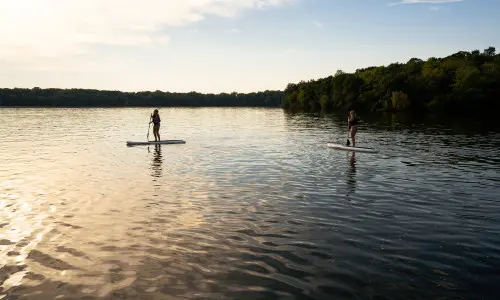 Dos personas practican paddle-boarding en un lago