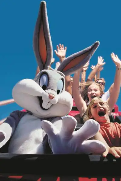 Niños en una montaña rusa con una persona disfrazada de Bugs Bunny