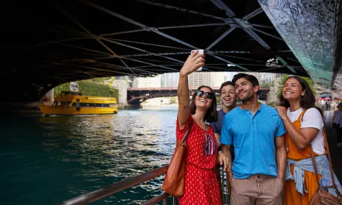 Gente posando para una foto junto al río bajo el puente 
