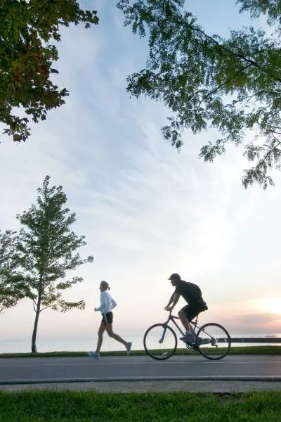 Una persona corriendo y otra en bicicleta por el carril bici frente al lago en Chicago