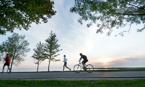 Una persona corriendo y otra en bicicleta por el carril bici frente al lago en Chicago