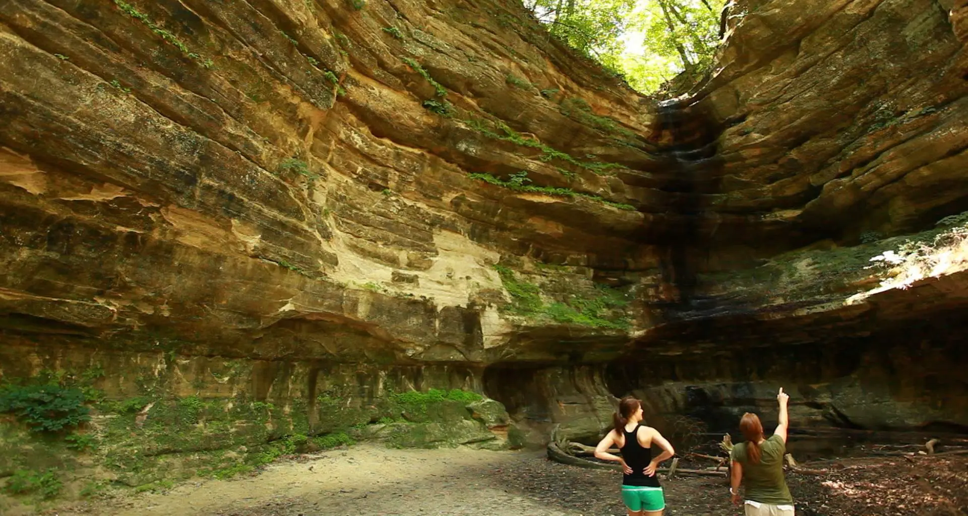 Dos personas mirando hacia la gran roca que rodea 