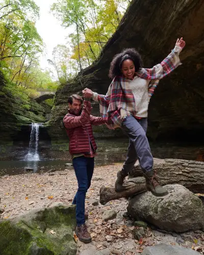 Dos personas trepando por las rocas frente a una cascada de roca