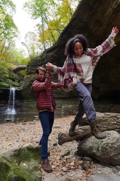 Dos personas trepando por las rocas frente a una cascada de roca