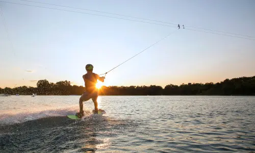 Una persona practicando esquí acuático al atardecer