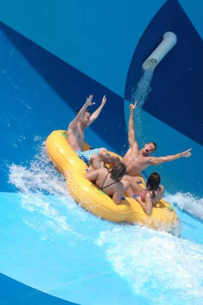Un grupo de cuatro personas en una balsa hinchable en un tobogán acuático