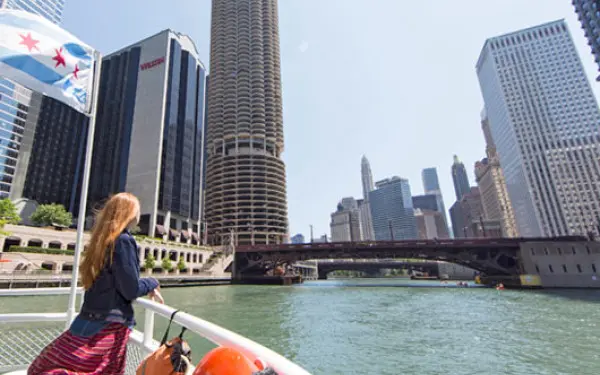 Una mujer se apoya en la barandilla de un crucero fluvial por el río Chicago , contemplando los edificios de la ciudad.