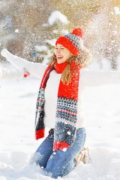 Una madre con su hijo abrigados para el tiempo y lanzando nieve al aire