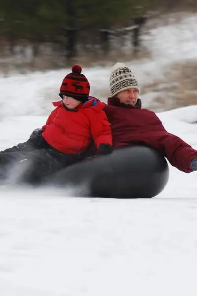 Un hombre y un niño practican snowtubing en el monte Hoy