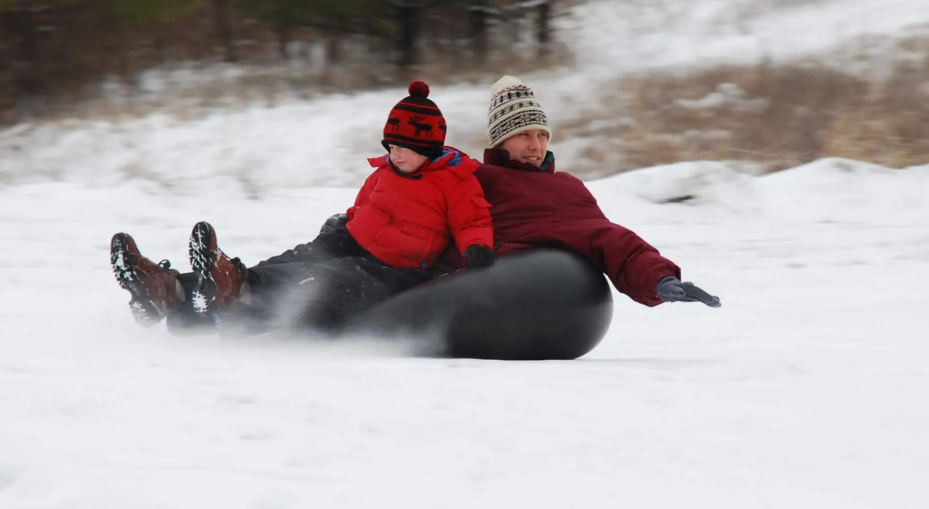 Un hombre y un niño practican snowtubing en el monte Hoy