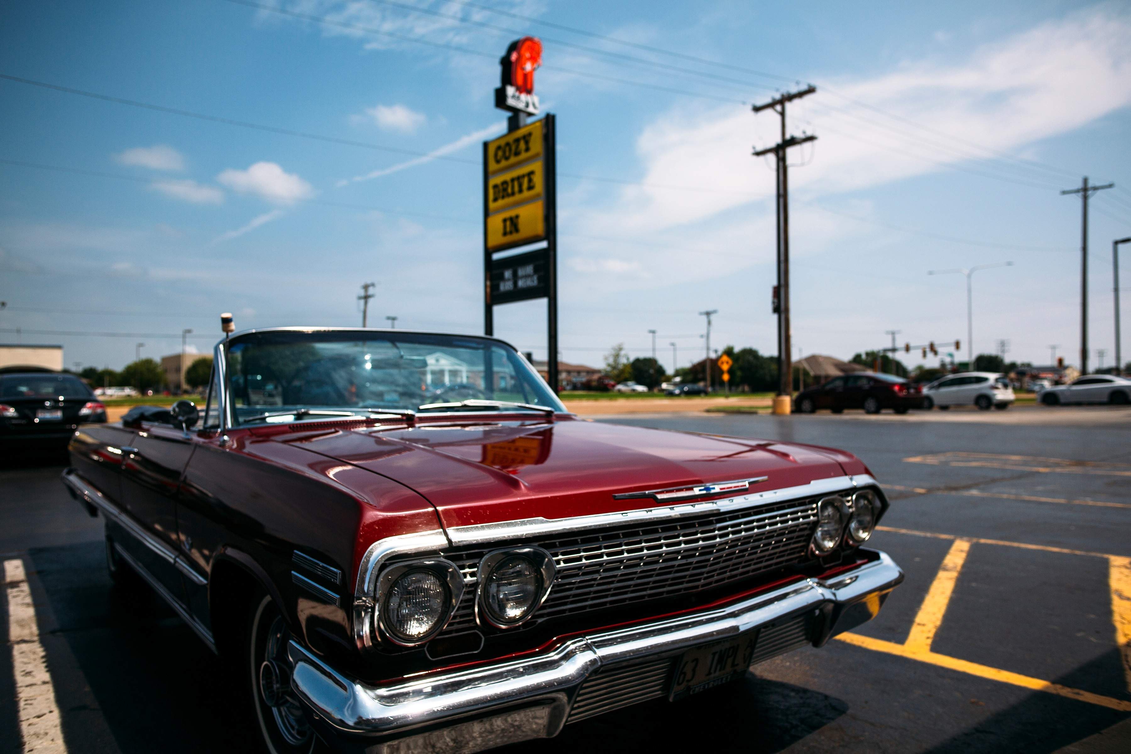 Coche aparcado cerca del cartel de Cozy Drive In