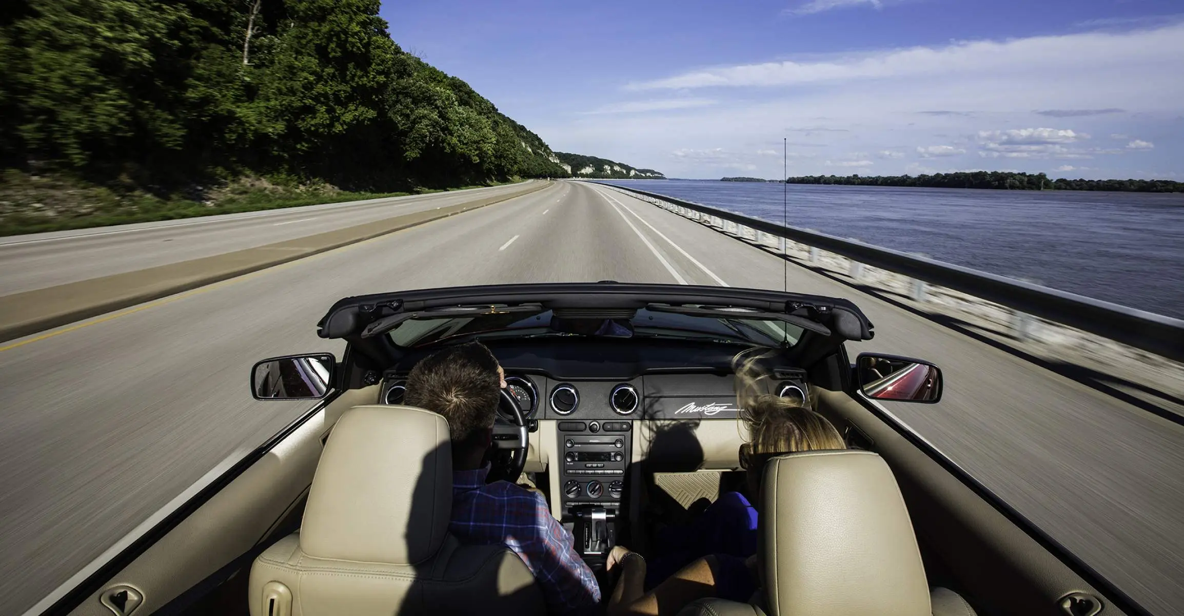 Dos personas circulan en un automóvil sin techo por una carretera