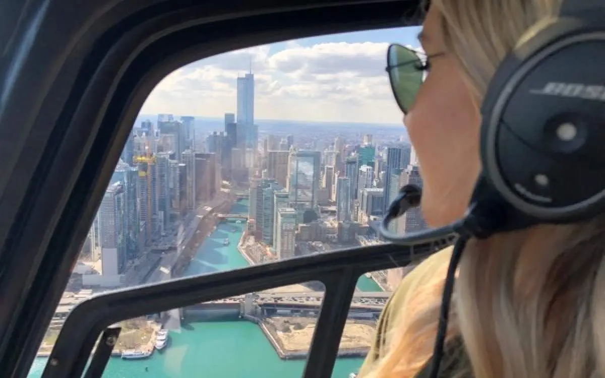 Una persona mirando por la ventana de un helicóptero los edificios de abajo
