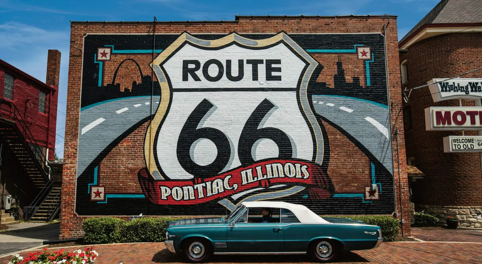 Mural de la Ruta 66 con un automóvil Pontiac delante.
