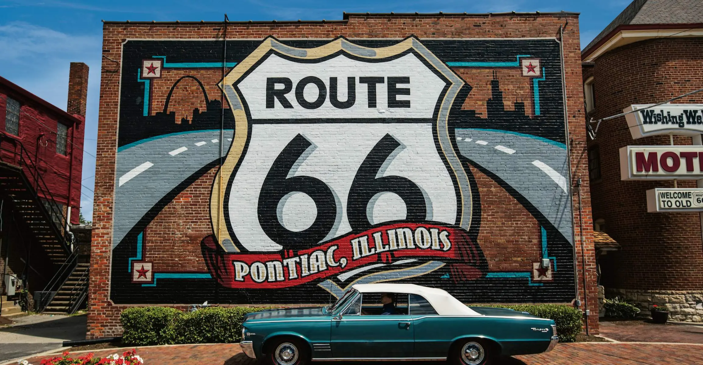 Mural de la Ruta 66 con un automóvil Pontiac delante.