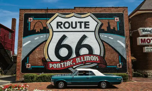 Mural de la Ruta 66 con un automóvil Pontiac delante.