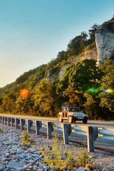 El amanecer brillando sobre el agua y un coche circulando por la carretera a su lado