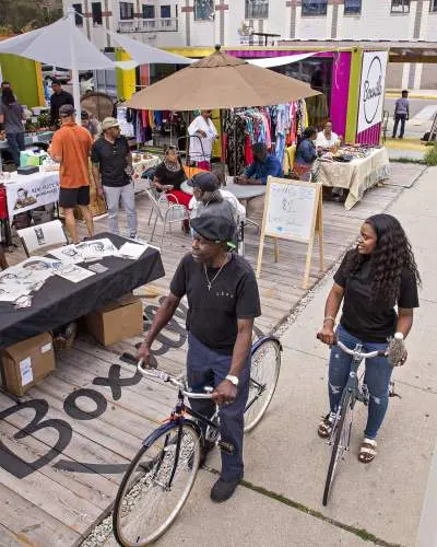 Dos personas en bicicleta frente a un mercado al aire libre