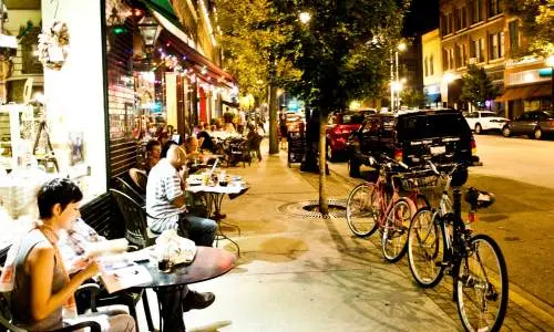 Gente leyendo y comiendo fuera de las tiendas a lo largo de la calle
