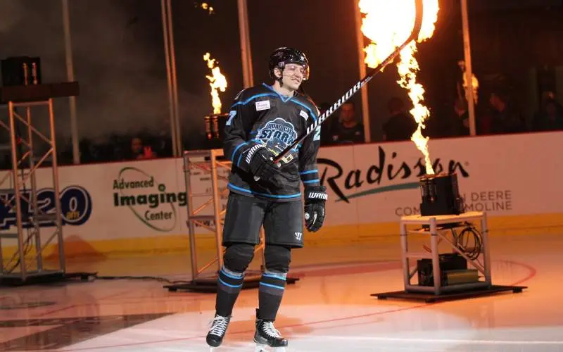 Jugador de hockey sosteniendo su stick delante de la pirotecnia