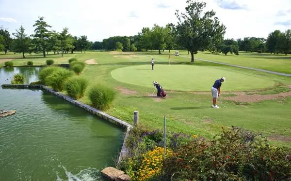 Golfistas jugando un partido en un green, junto a una fuente de agua