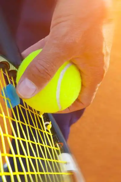 Primer plano de alguien preparándose para servir una pelota de tenis